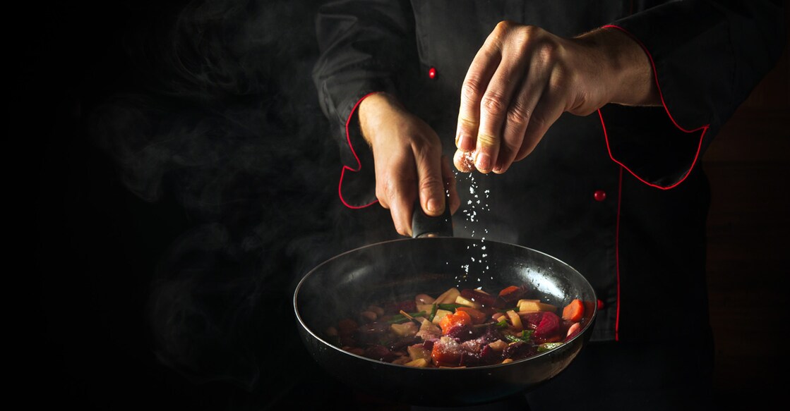 Adding salt while cooking. Photo: Shutterstock/VITALII BORKOVSKYI
