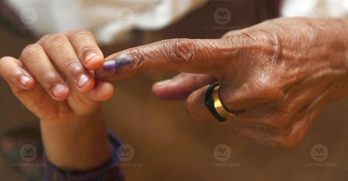 A child holds on to an elderly woman's finger after voting. File Photo: Manorama