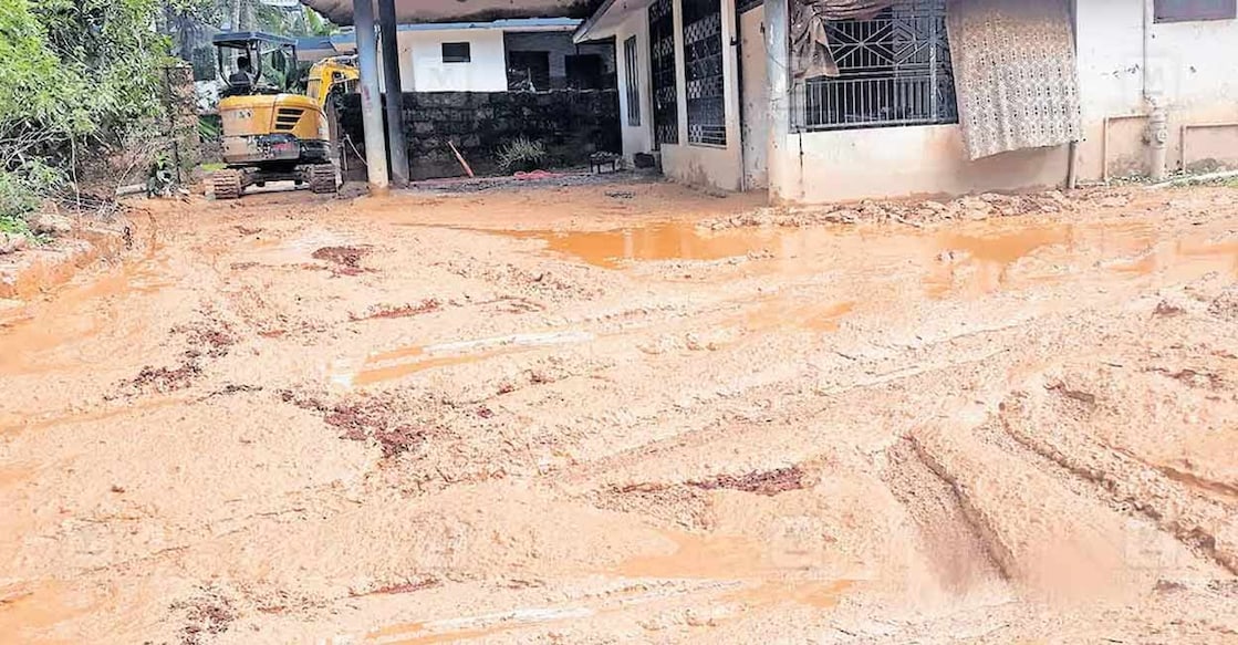 The area in front of PV Kunjamina's house in Kuppam CH Nagar remains muddy. A National Highway construction company's earthmover is also seen removing the mud. Photo: Special arrangement