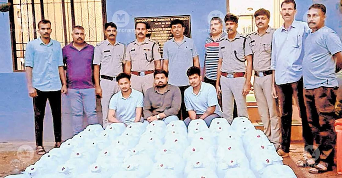 The cans of spirit seized during transport in a mini-lorry, along with the accused (sitting), and the police team that apprehended them. Photo: Special arrangement