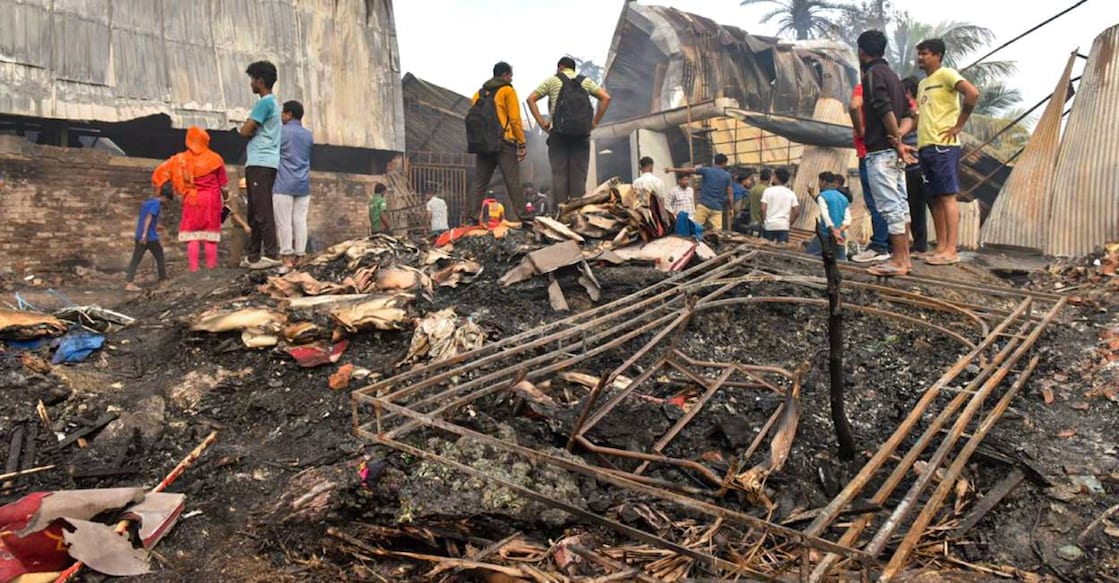 People gather near the charred remains of a fire at a warehouse, in Kolkata. Photo: PTI