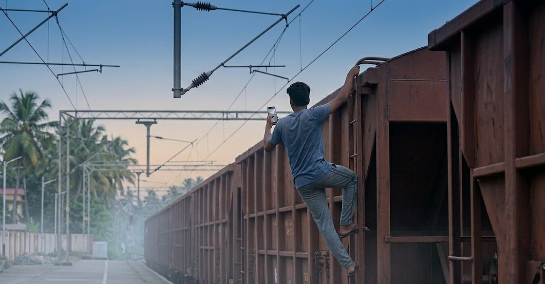 An AI-generated image showing a youth attempting to climb atop a goods train to take a selfie. 