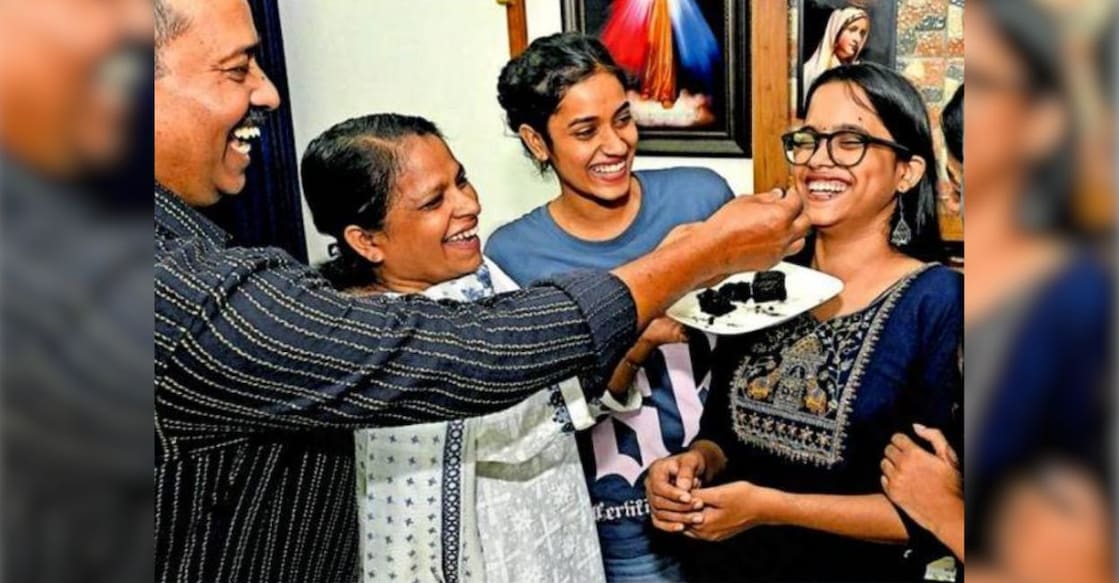 Maria Kripa Michael of Sacred Heart HSS, Thevara, who scored full marks in her Plus Two examinations, being offered sweets by her father Michael Antony and mother Sheela. Photo: Manorama