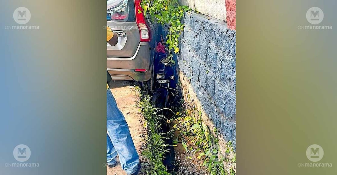 A car that fell into the open drain near Kadanthottu bridge on MK Road in Chengannur, with a motorbike also seen caught in between. Photo: Special arrangement