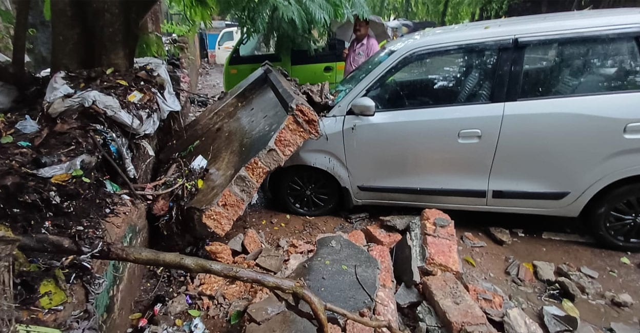 A section of the boundary wall within the Comtrust premises in Kozhikode collapsed onto a parked car during heavy rain on Friday morning. Photo: Special Arrangement