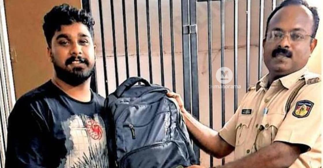 Railway Police CPO Rajesh Kumar hands over the recovered bag containing camera equipment worth nearly Rs 7 lakh to photographer Shone Dominic at Kottayam railway station. Photo: Special Arrangement.