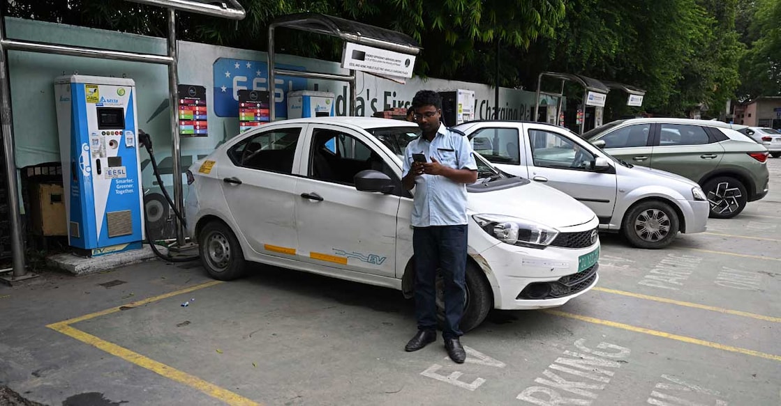 In this photograph taken on July 27, 2023, a driver uses his phone while charging an electric car at an electric automobile charging station in New Delhi. Photo: AFP/Money Sharma 