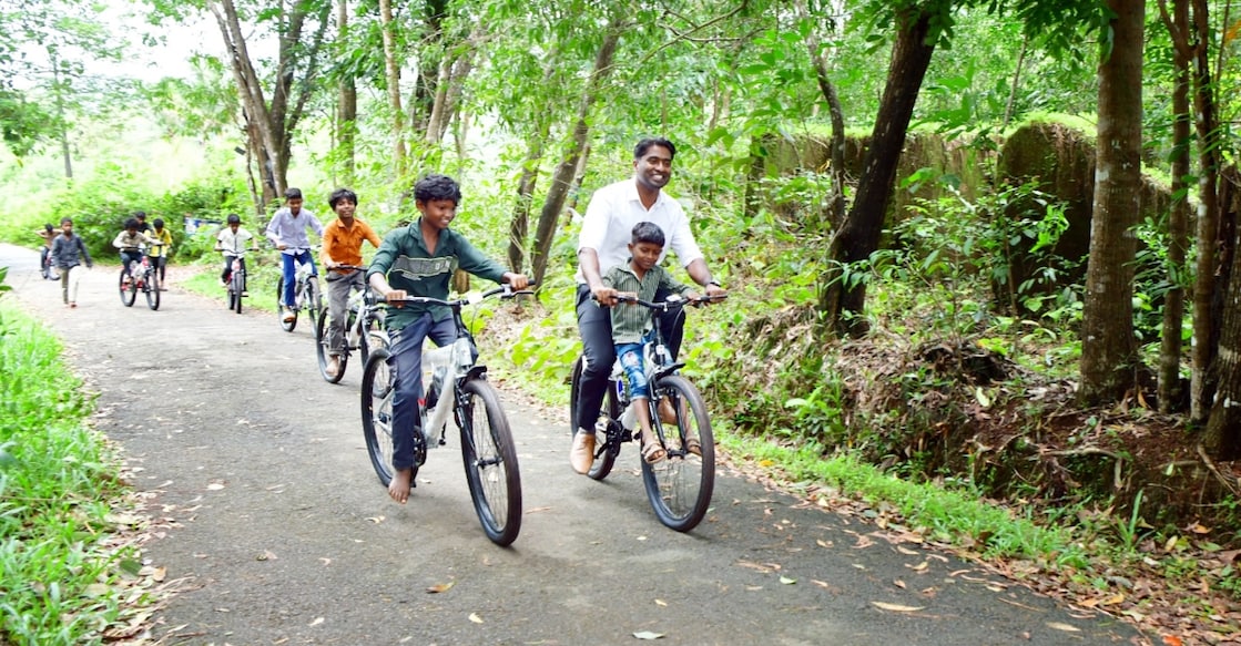 Kasaragod Collector Arjun Pandian riding with children on their newly gifted bicycles. Photo: Special arrangement