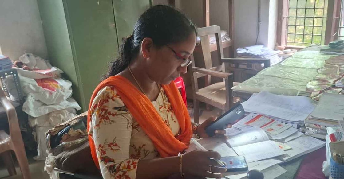 Staff at Ramdas Nagar Post Office in Kasaragod's Madhur panchayat use flashlight on mobile phone to examine documents. Photo: Special arrangement