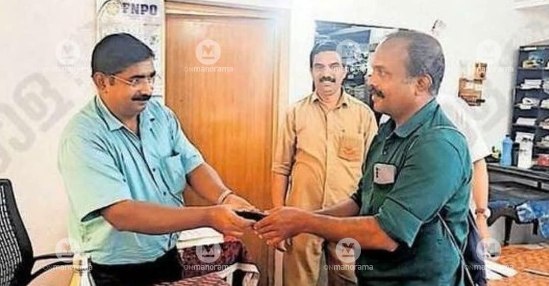 Postmaster A Abraham of Cherupuzha Post Office hands over a purse found in a letterbox to its owner, K V Rajeevan. Photo: Special Arrangement.
