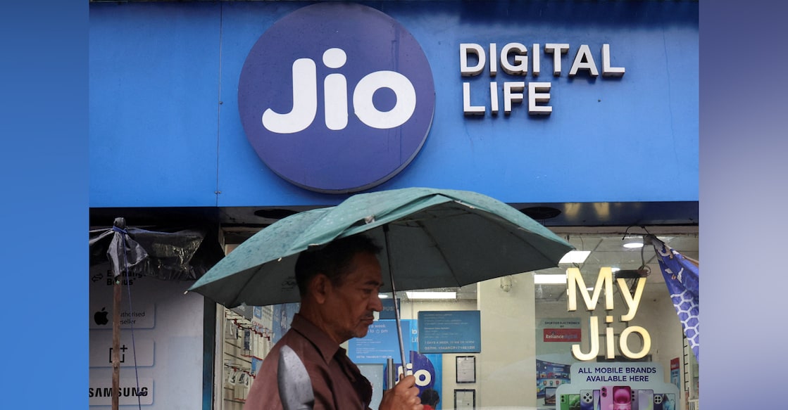 A man walks with an umbrella in front of a Reliance Industries' Jio Digital Life store on a street in Kolkata. Photo: Reuters