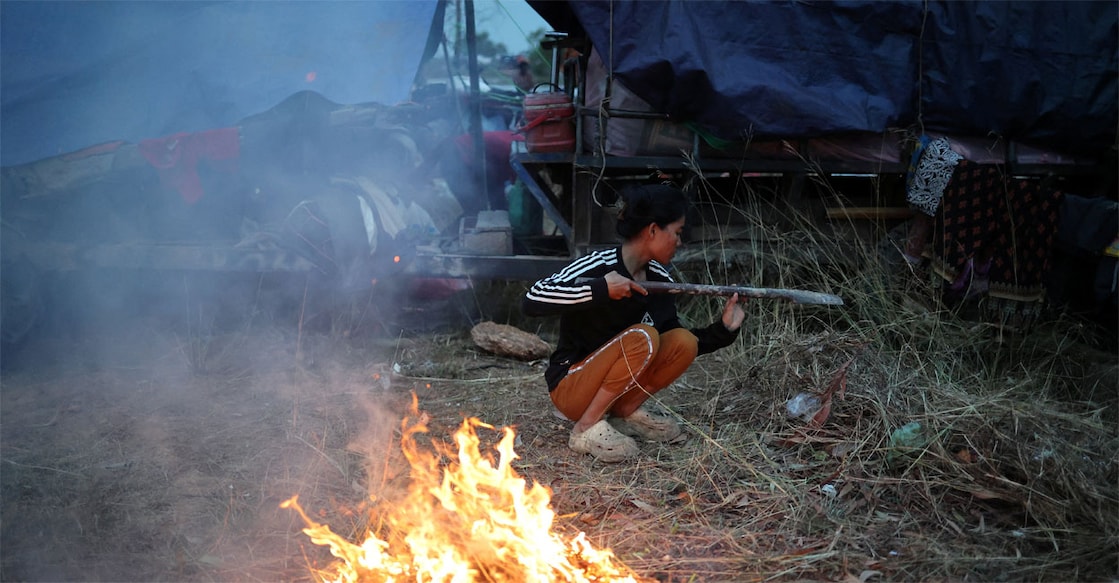 A woman burns grass to keep warm in a refugee camp after evacuation, amid deadly clashes between Thailand and Cambodia along a disputed border area, in Srei Snam, Siem Reap Province. Photo: REUTERS/Kim Hong-Ji