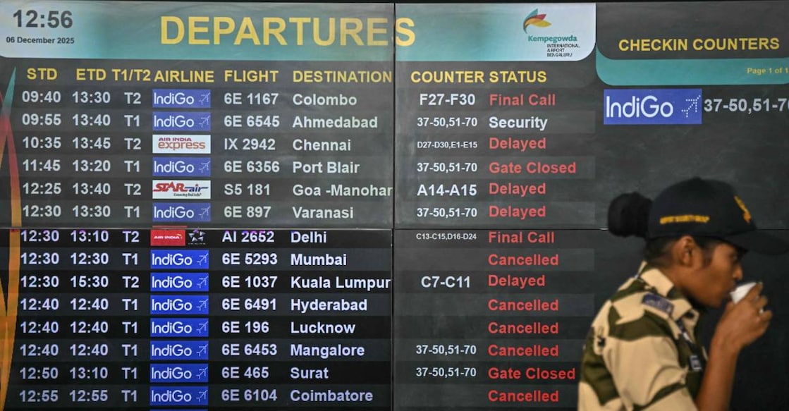 A security personnel stands beside a digital departures board displaying flight information at Kempegowda International Airport in Bengaluru. Photo: PTI