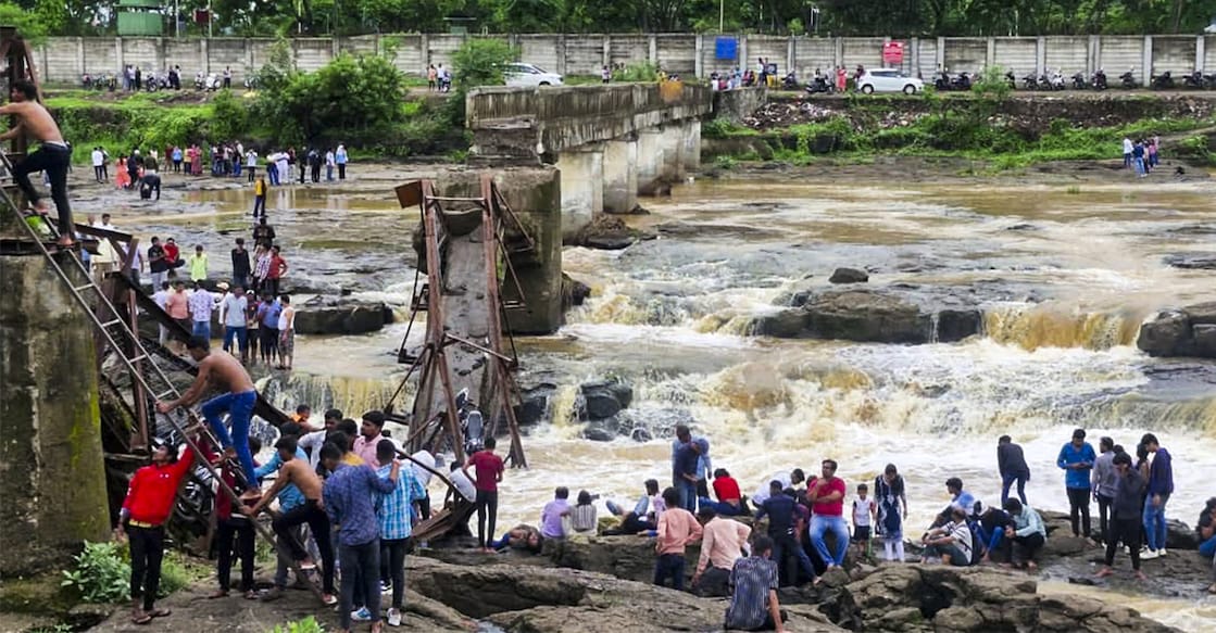People stand near an iron bridge over the Indrayani river after it collapsed, in Pune district, Maharashtra. Photo: PTI