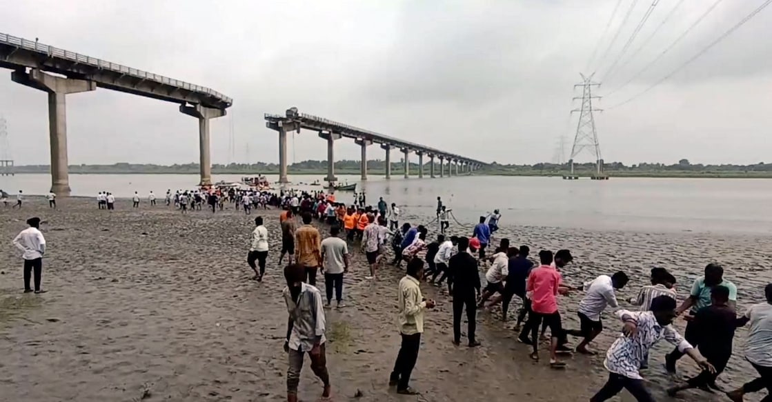 People pull a vehicle out of the Mahisagar river, after multiple vehicles plunged into the river after a portion of a four-decade-old bridge collapsed, through a rope, in Vadodara district. Photo: PTI