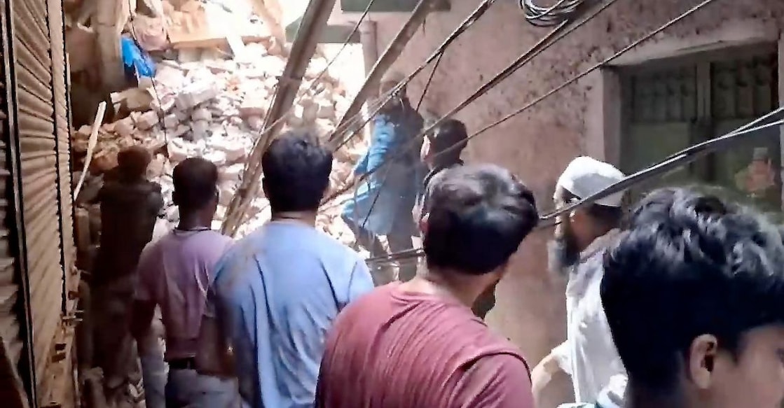 Rescue personnel and locals stand near debris amid a rescue operation after the building collapsed in Delhi. Photo: PTI