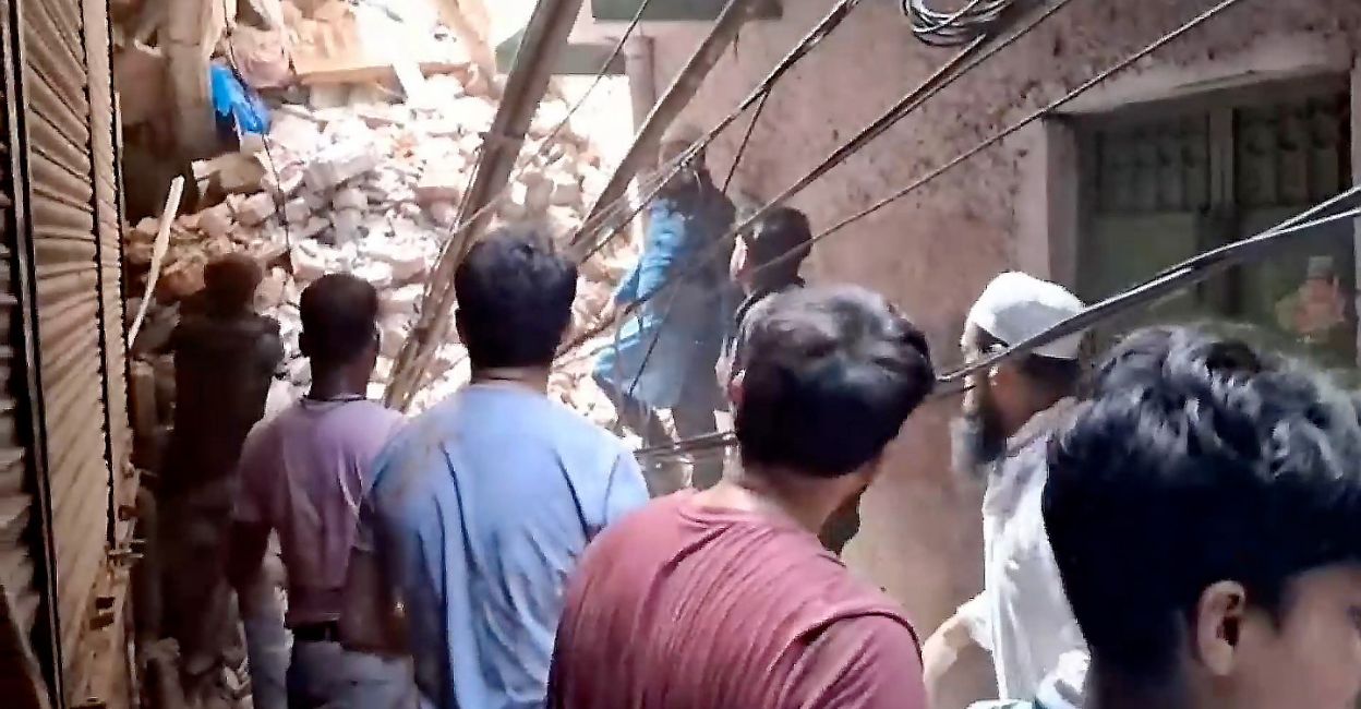 Rescue personnel and locals stand near debris amid a rescue operation after the building collapsed in Delhi. Photo: PTI