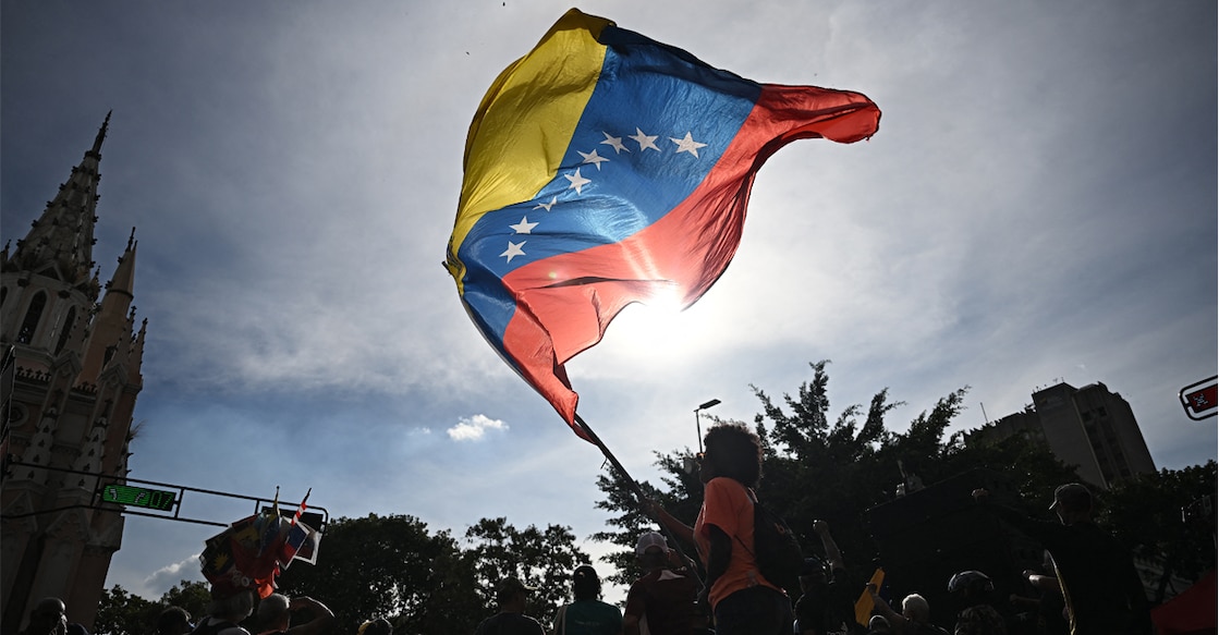 A person flutters a national flag in Caracas on January 3, 2026, after US forces captured Venezuelan leader Nicolas Maduro. Photo: FEDERICO PARRA / AFP