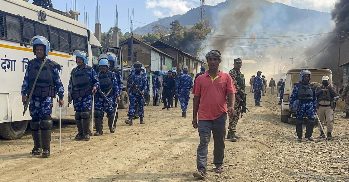 Security personnel gather as smoke billows after armed miscreants allegedly set fire to houses at Litan Sareikhong village in Ukhrul. Photo: PTI