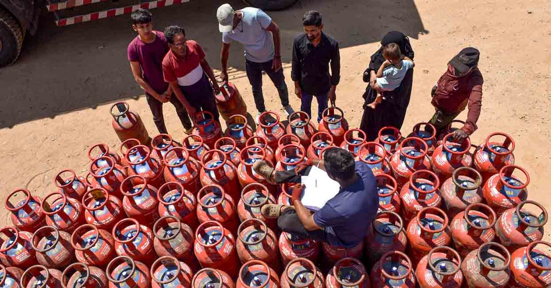 A worker sits over LPG cylinders as people arrive to collect them at a gas agency, in Chikkamagaluru, Karnataka, Wednesday, March 11, 2026.  Photo: PTI