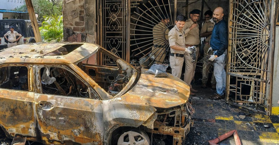 Police personnel gather near the wreckage of a car after a fire broke out in a house, in Indore, Madhya Pradesh on March 18. Photo: PTI
