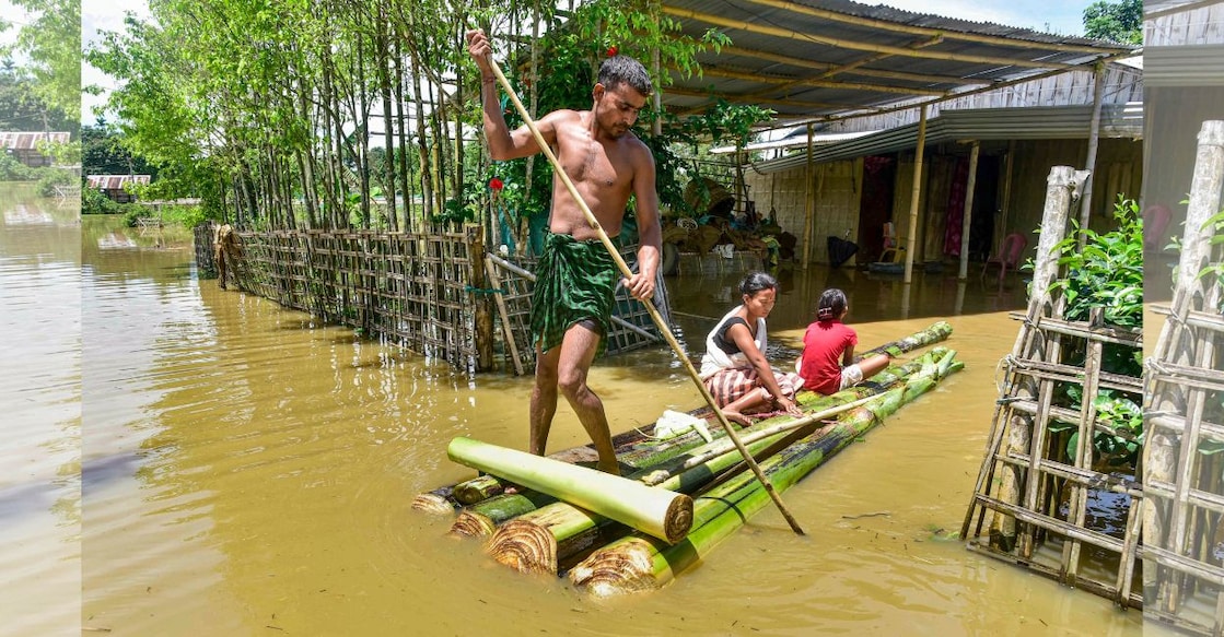 People cross a flood-affected area on a makeshift raft after heavy rainfall in Golaghat, Assam. Photo: PTI