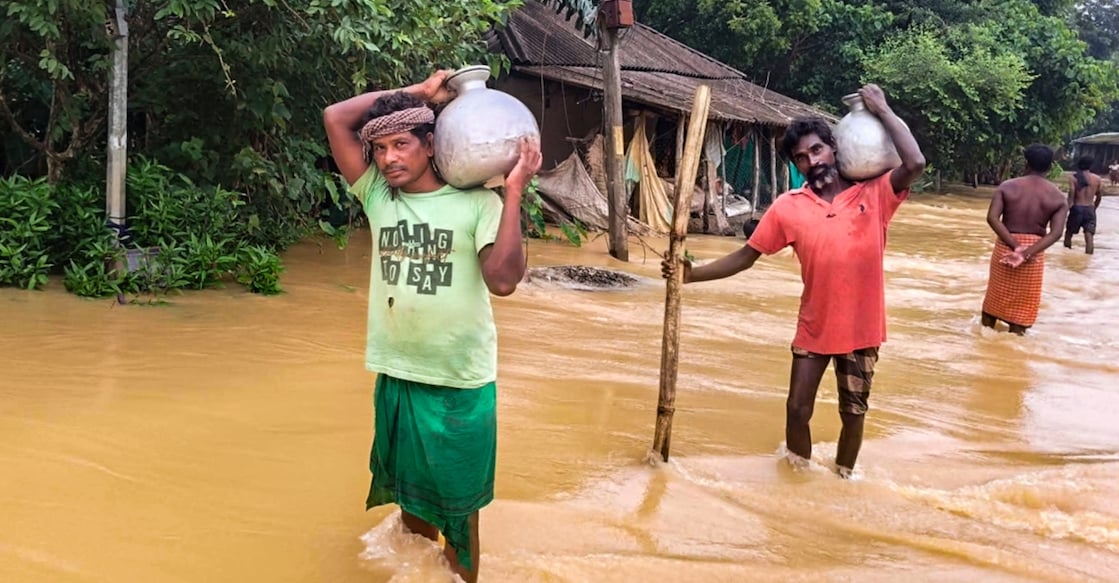 Residents of Mathani village in Basta carry drinking water as their village remains inundated due to floods in Baleswar district of Odisha on Aug. 15, 2026. Photo: PTI 

