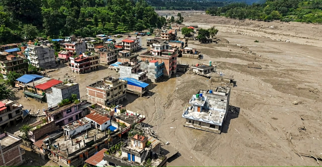 A view of structures standing partially submerged in a thick layer of mud and debris following flash floods at Beni Ghat area, in Dhading district, Nepal. Photo: PTI