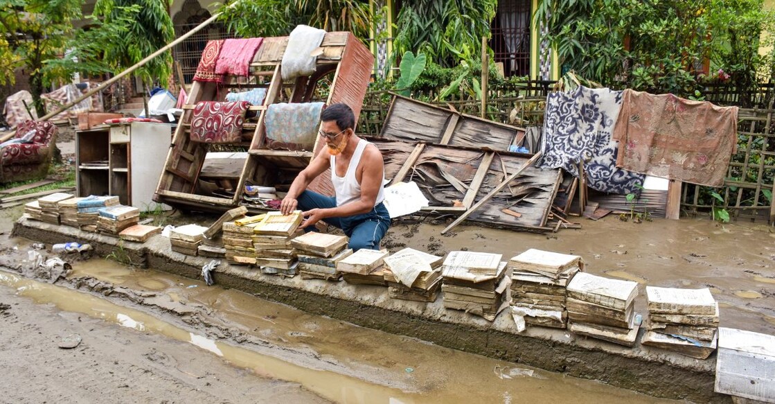 An advocate dries flood-damaged legal books and documents outside his residence after floodwaters receded in Santak of Sivasagar district in Assam on August 3. Photo: PTI 