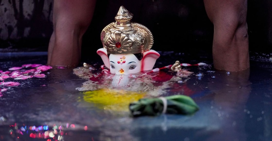 A person immerses a Lord Ganesh idol in an artificial pond at Shivaji Park after one and a half days of worship during the Ganesh Chaturthi festival in Mumbai. Photo: PTI. 