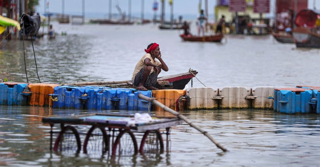 A man sits on a floating barricade amid floodwaters along the partially submerged banks of the Ganga following heavy rainfall, in Prayagraj, Uttar Pradesh. Photo: PTI 