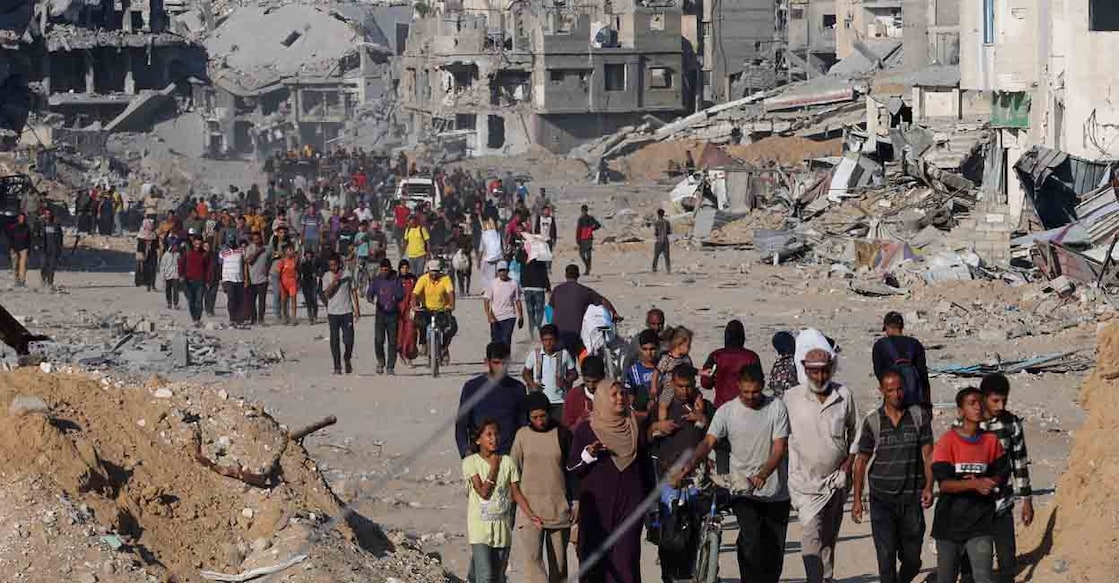 Palestinians walk past rubble as they return to their neighborhood, following Israeli forces' withdrawal from the area, amid a ceasefire between Israel and Hamas in Gaza, in Khan Younis, in the southern Gaza Strip October 11, 2025. REUTERS/Ramadan Abed