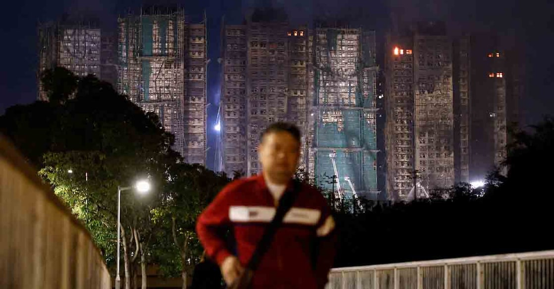 A man walks near the scene of a deadly fire, which broke out yesterday at Wang Fuk Court housing complex, as efforts to extinguish it continue, in Hong Kong, China November 27, 2025. REUTERS/Maxim Shemetov     TPX IMAGES OF THE DAY