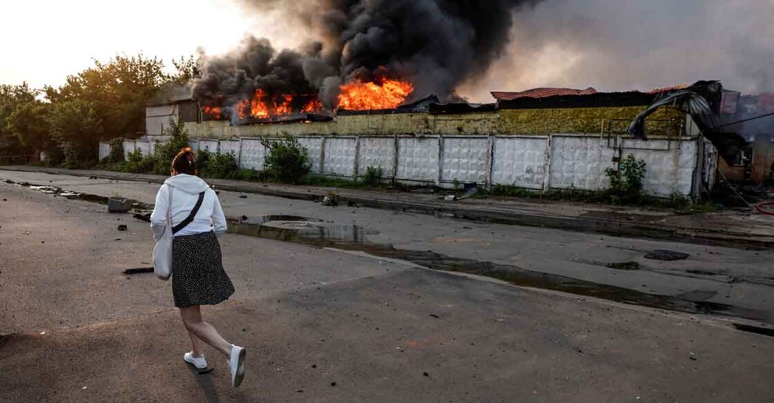 UKRAINE-CRISIS-ATTACK-KYIV A passerby walks near a building on fire at the site of a Russian drone strike, amid Russia's attack on Ukraine, in Kyiv, Ukraine June 10, 2025. REUTERS/Thomas Peter