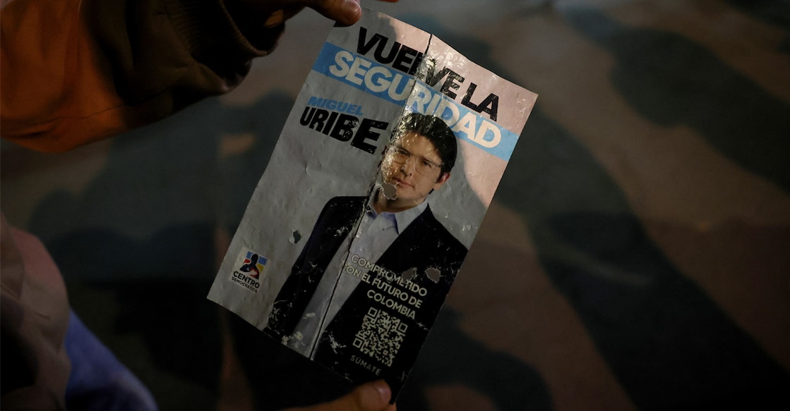 A persin holds a campaign poster at the area where Colombian Senator Miguel Uribe Turbay of the opposition Democratic Center party, was shot during a campaign event, in Bogota. Photo: REUTERS/Luisa Gonzalez