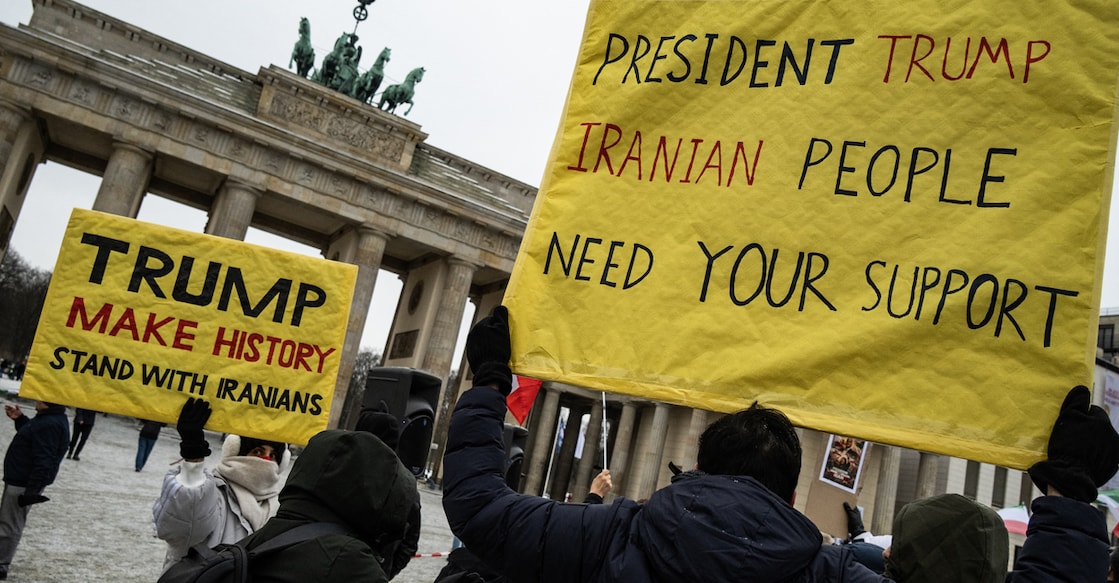 Demonstrators display placards calling for the US President to intervene in Iran during an anti-Iranian-government protest in front of the Brandenburg Gate in Berlin, Germany, on January 12, 2026. Photo by John MACDOUGALL/AFP