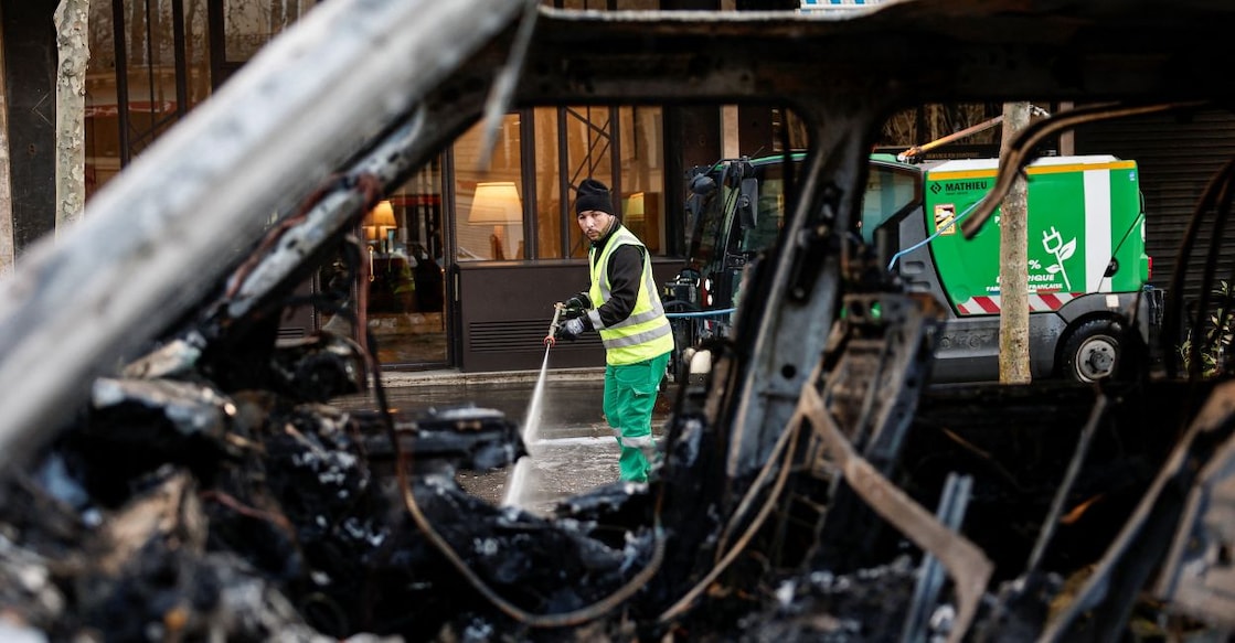 A municipal worker, seen through a burnt-out car, cleans a street a day after clashes during a national day of demonstrations against the cost of living and rising fuel prices in Paris, France. Photo: Reuters. 