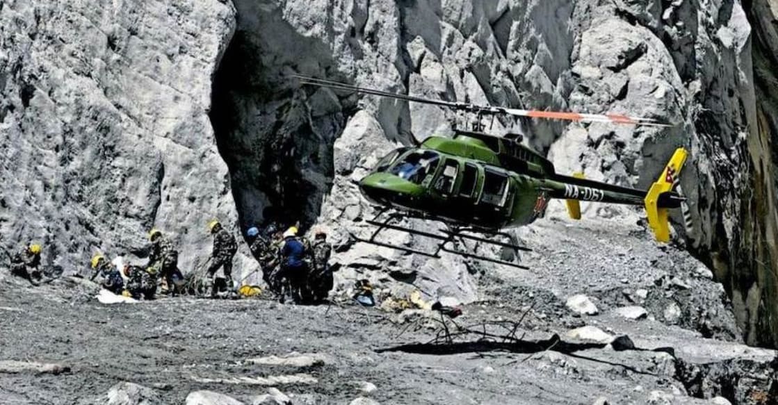 A Nepal Army helicopter lands on a makeshift helipad built with wooden logs to rescue people trapped inside a tunnel at an under construction hydropower project in Syabrubesi, Nepal. The site was covered in mud following the floods. Photo: Manorama