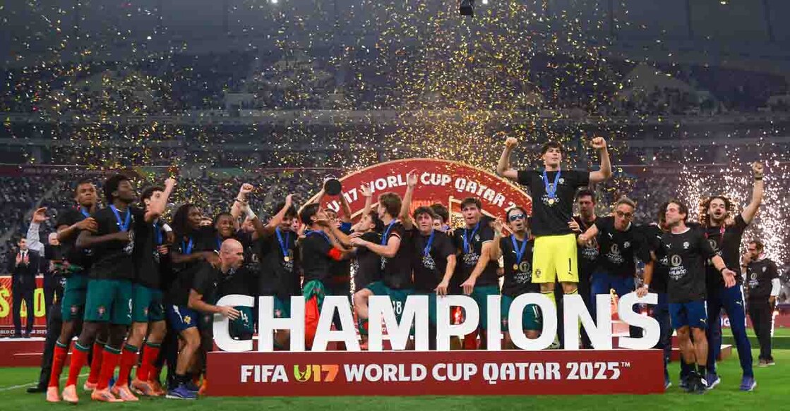 Portugal's players celebrate with the trophy on the podium after the FIFA U17 World Cup final football match between Portugal and Austria at Khalifa International Stadium in Al-Rayyan on November 27, 2025. (Photo by Karim JAAFAR / AFP)
