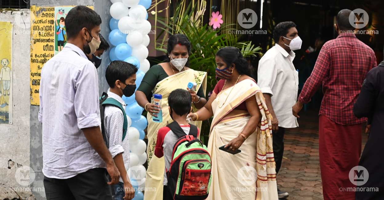 school-reopening-2 School staff at the Government Higher Secondary School, Muppathadam, Ernakulam, distributing sanitizer and checking temperature of students on the 'Pravesanolsavam' day as schools reopen in Kerala for physical classes after one-and-a-half years. Photo: Josekutty Panackal
