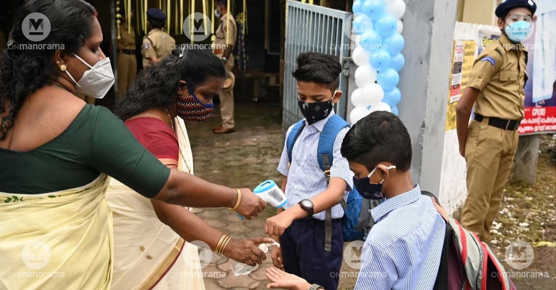 School staff at the Government Higher Secondary School, Muppathadam, Ernakulam, distributing sanitizer and checking temperature of students on the 'Pravesanolsavam' day as schools reopen in Kerala for physical classes after one-and-a-half years. Photo: Josekutty Panackal