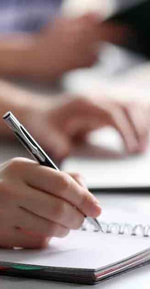 Exam Student's hand writing in exercise book at the table