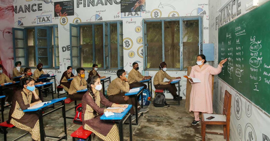 Students wearing protective face masks inside a classroom of a government-run school after authorities ordered schools to reopen for classes 10 to 12, in Patiala. PTI