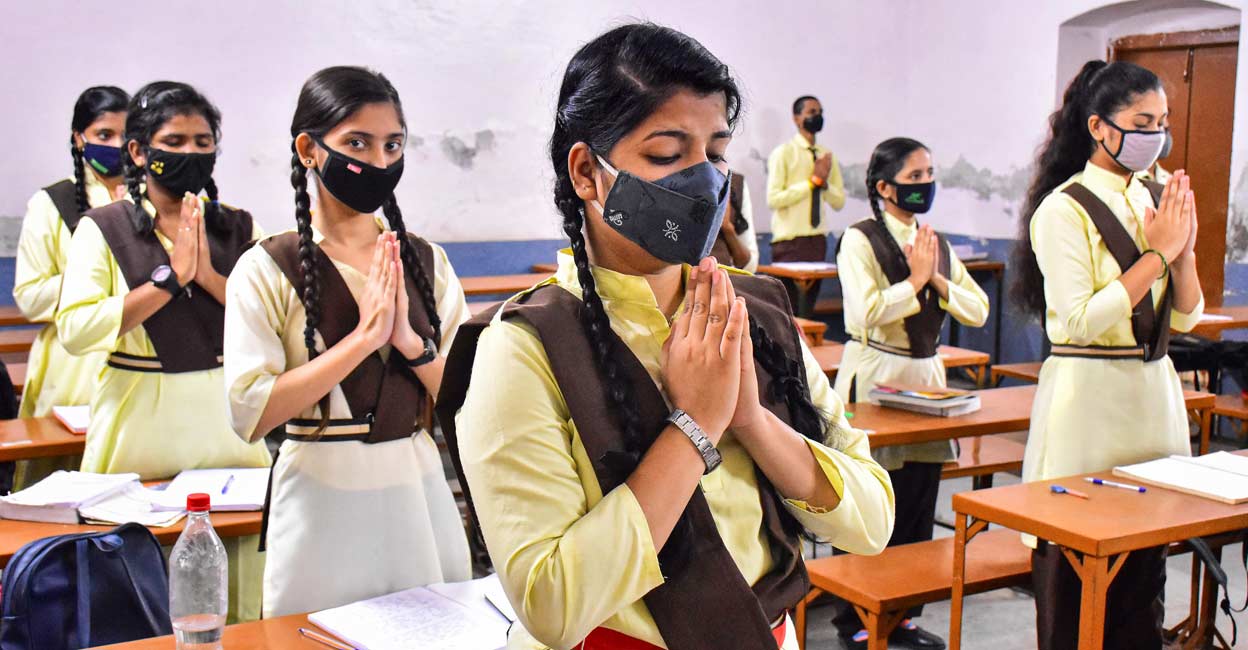 Students wearing face masks join a prayer in the classroom of a school that reopened after further ease in COVID-19 lockdown restrictions in Jabalpur. PTI