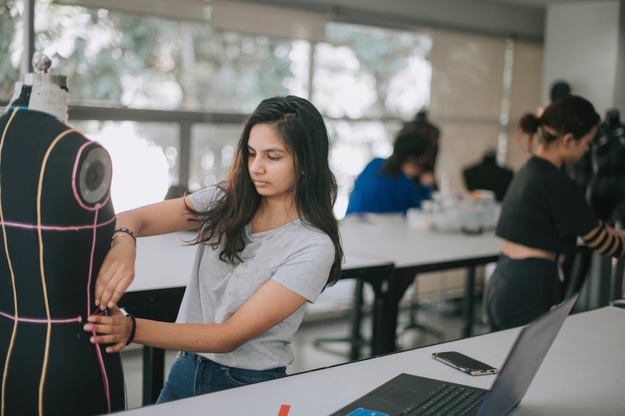 college fashion student attending class in the classroom working on their fashion design