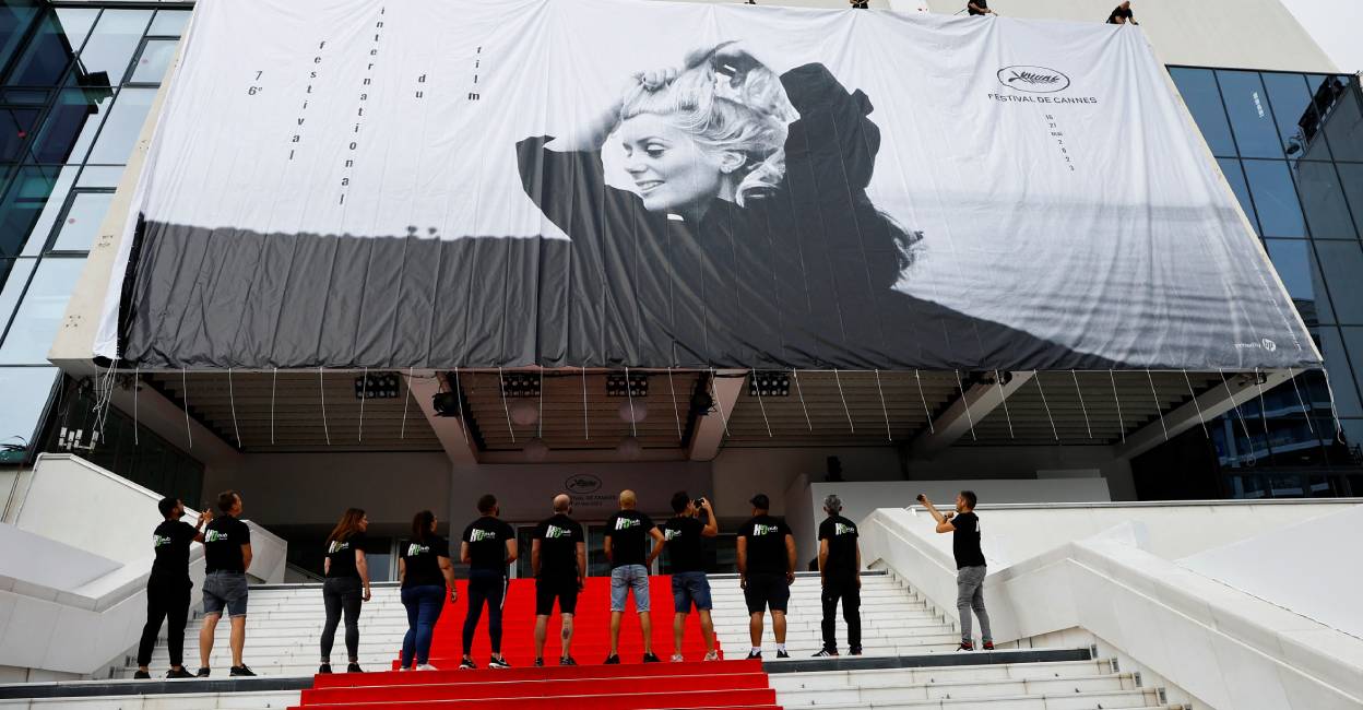 Workers set up a giant canvas of the official poster featuring Catherine Deneuve in the film La Chamade, on the facade of the festival palace ahead of the opening ceremony. Photo: Reuters