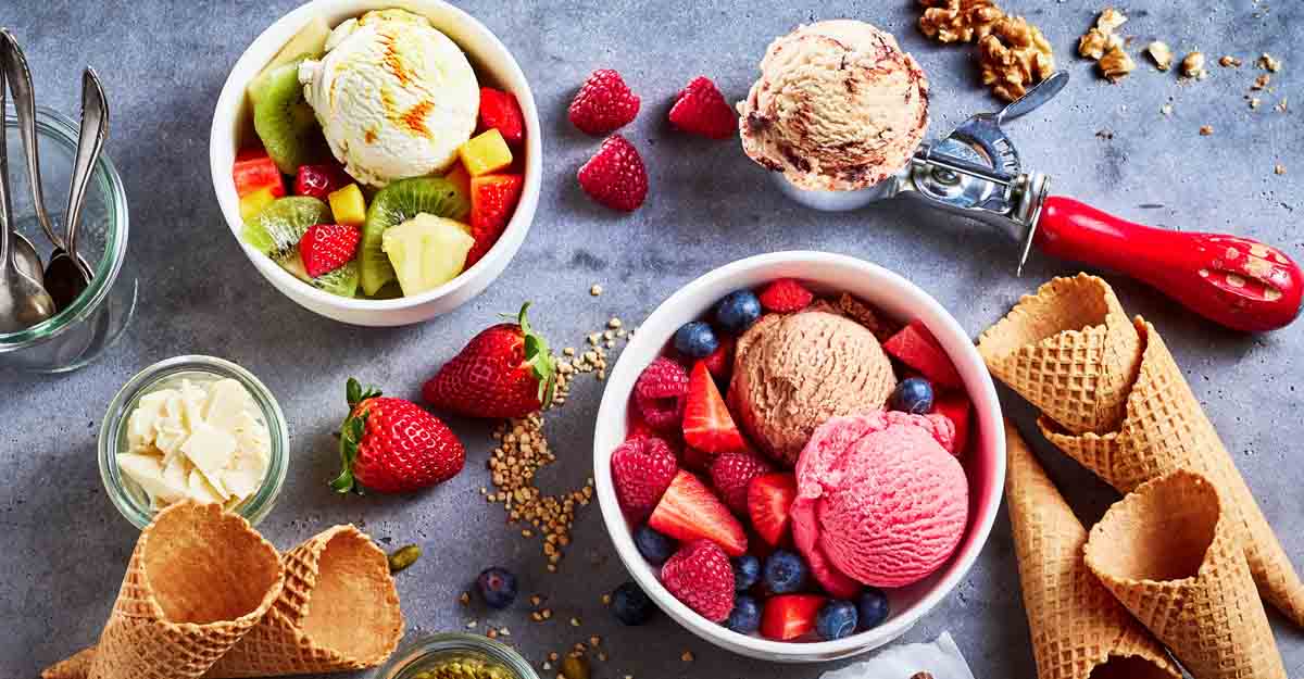 Ice cream Fresh fruit with scoops of creamy speciality ice cream in assorted flavors with raspberry, berry, blueberry, strawberry, walnut , pistachio, chocolate, sugar cones and a scoop for serving. Photo: Shutterstock/stockcreations
