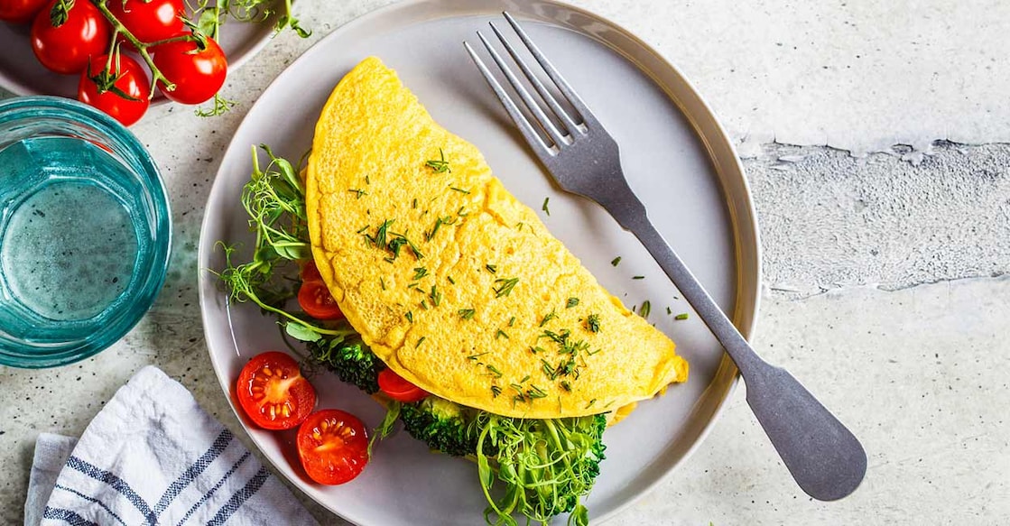Vegan egg omelette Vegan chickpea omelet with broccoli, tomatoes and seedlings on a gray plate. Photo: iStock/vaaseenaa