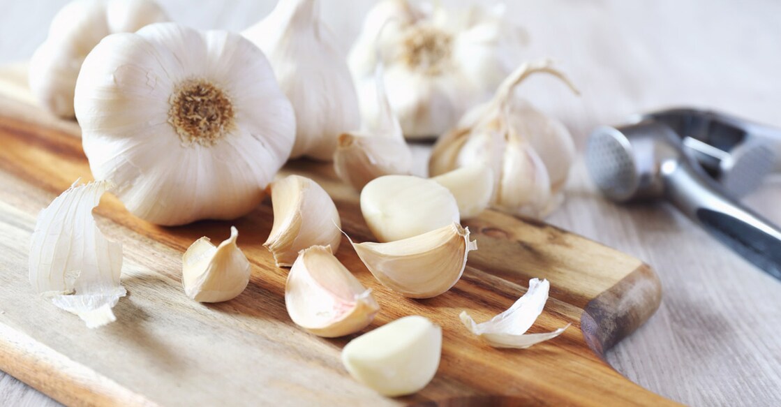 Bulbs of garlic on cutting board. Photo: iStock/photosimysia