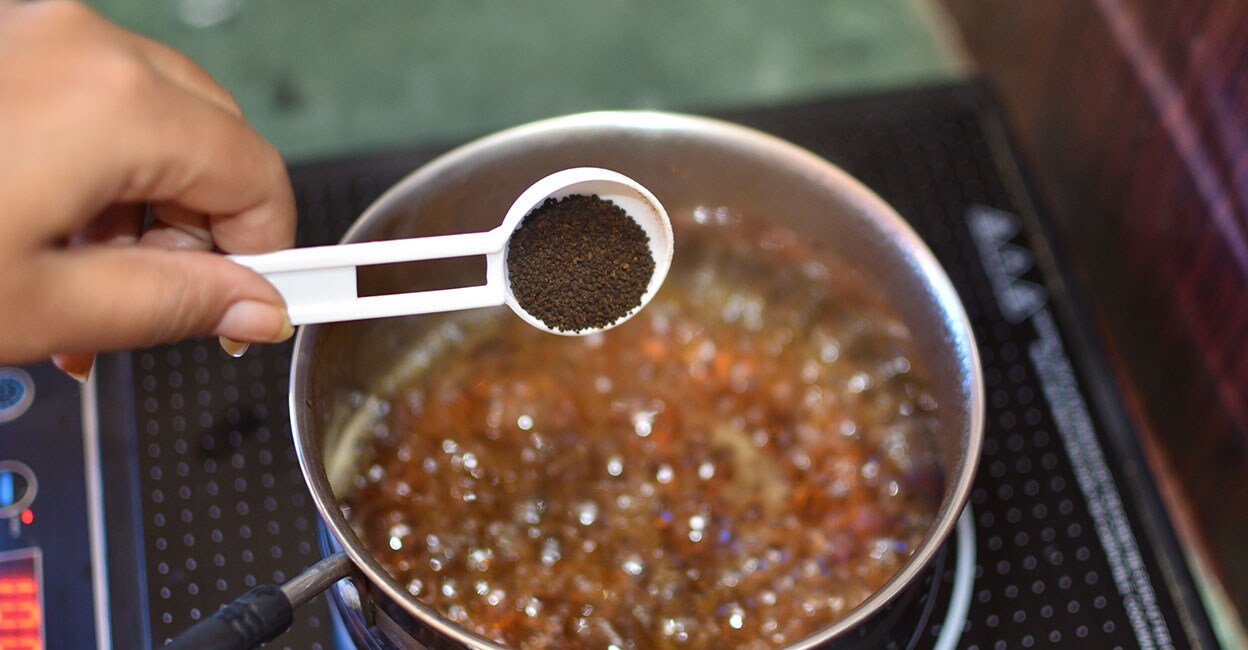 Adding black tea leaves and a pinch of herb mixture to boiling water. Photo: iStock/SOMNATH MAHATA